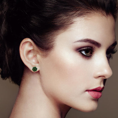 Close-up side view of a model wearing white metal stud earrings adorned with round green gemstones in a cluster prong setting.
