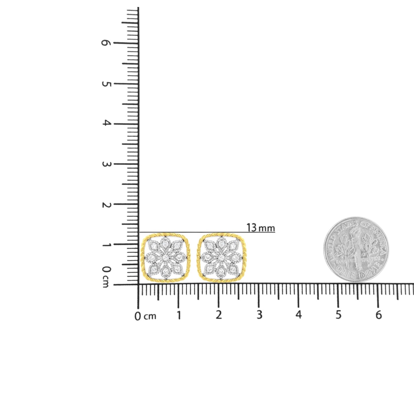 Pair of yellow metal earrings with a cushion-shaped frame and floral design of white gemstones, shown on a ruler for size reference, front angle.
