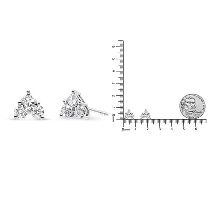 Pair of white metal earrings with a triangular arrangement of one princess-cut and three round-cut white gemstones, shown at a front and side angle next to a ruler and coin for size reference.