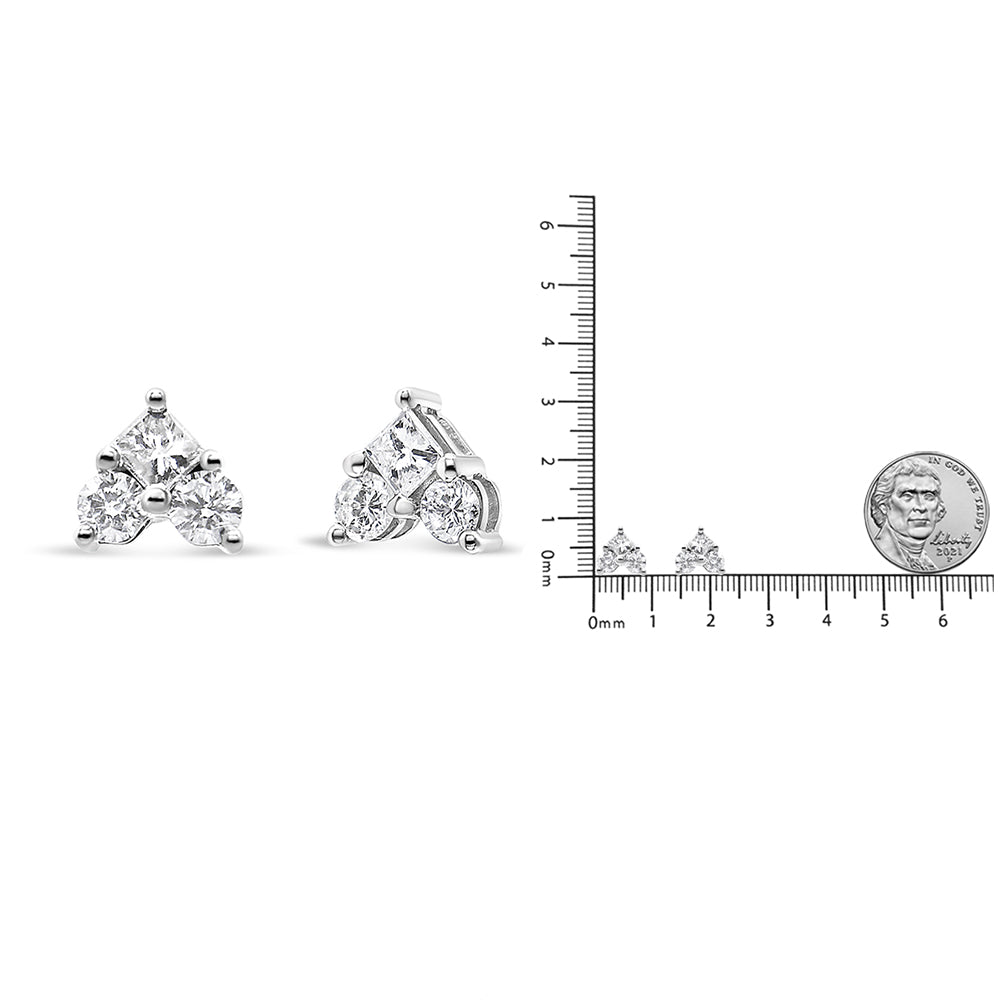 Pair of white metal earrings with triangular design featuring a princess-shaped white gemstone and round white gemstones, shown from front and side angles next to a ruler and coin for size reference.