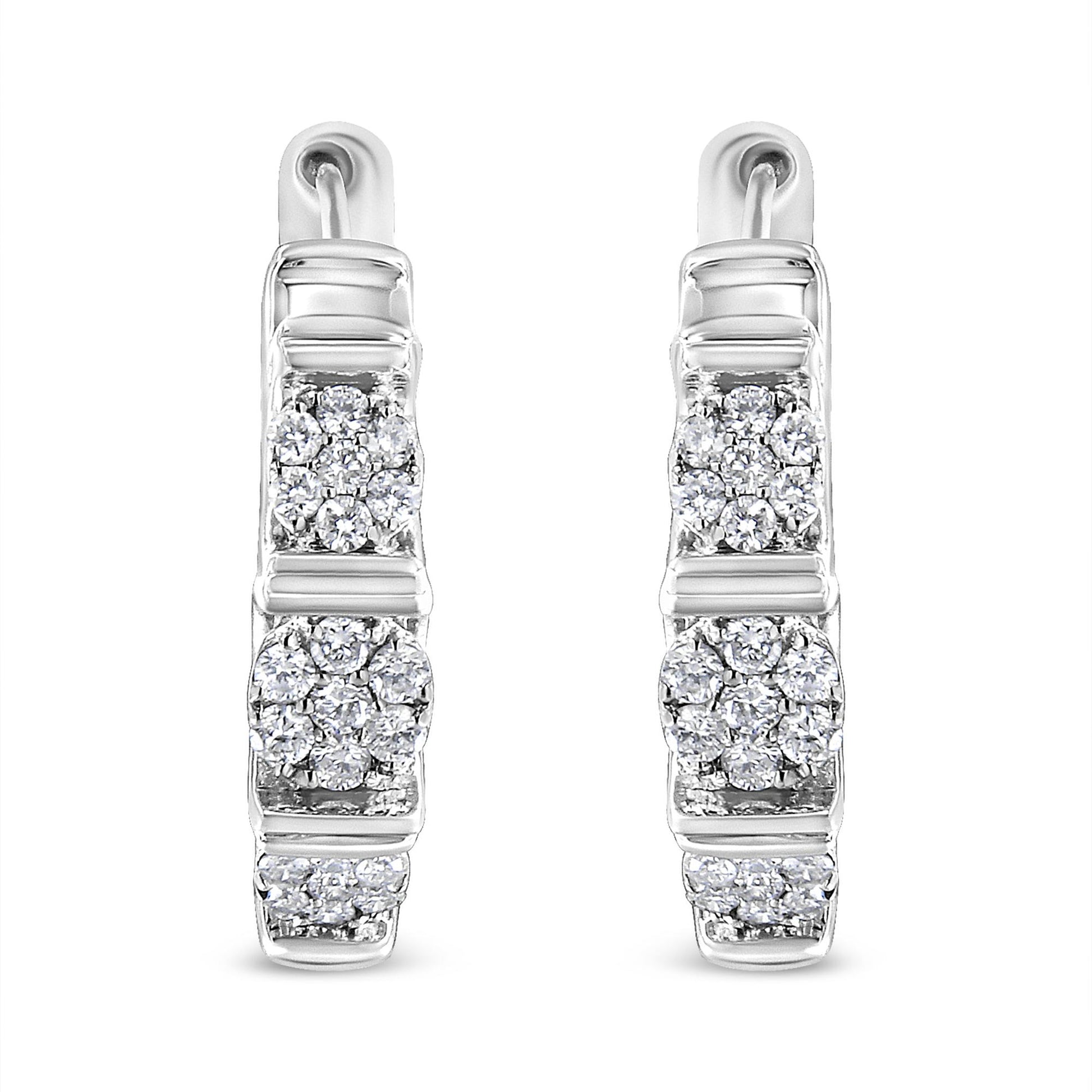 Front-facing shot of white metal hoop earrings with clusters of round white gemstones in prong settings arranged vertically.