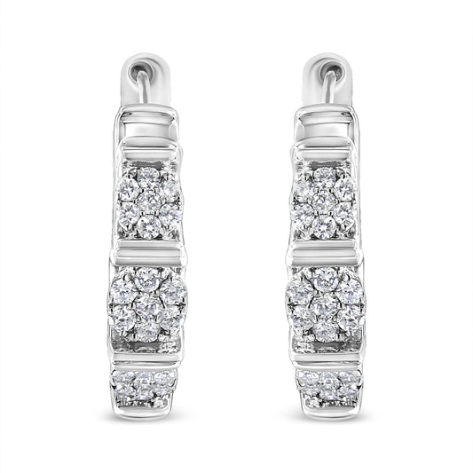 Front-facing shot of white metal hoop earrings with clusters of round white gemstones in prong settings arranged vertically.