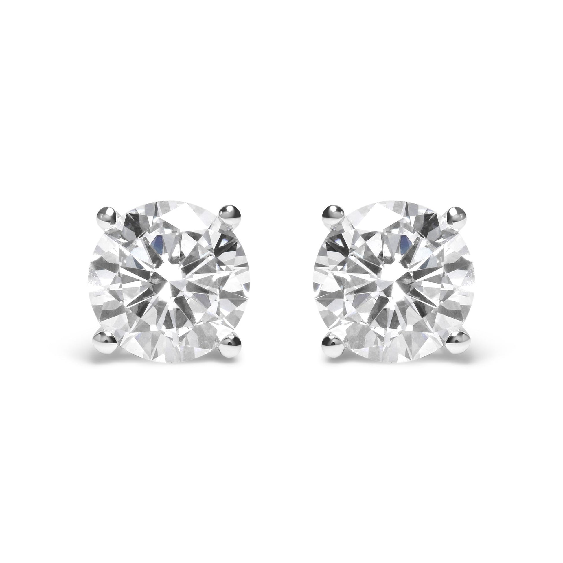 Pair of white metal stud earrings with round white gemstones in 4-prong settings, front view.