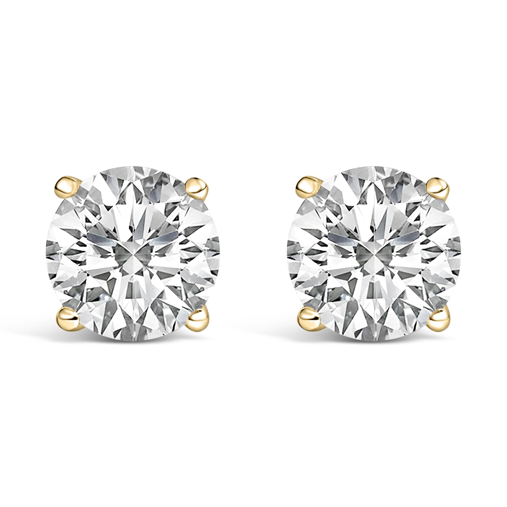 Front view of yellow metal stud earrings, each featuring a round white gemstone in a four-prong setting, shown against a white background.