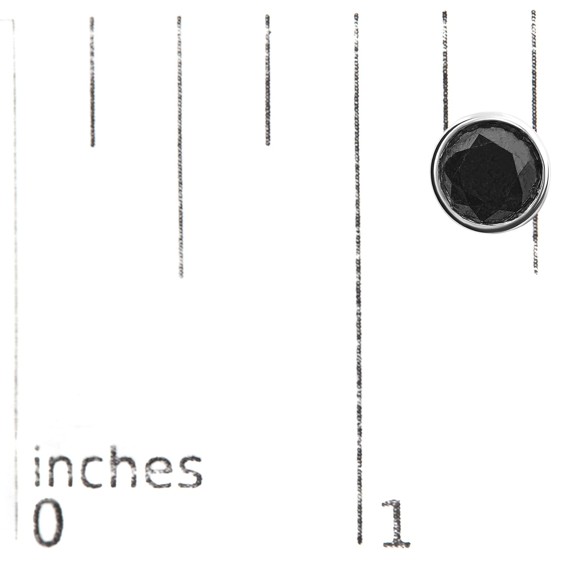 Top view of a white metal round stud earring with a black gemstone in bezel setting, placed on a ruler for size reference.