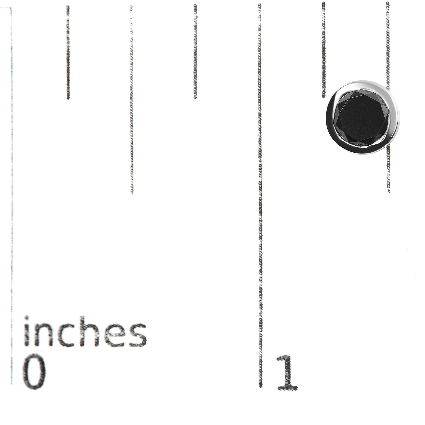 Close-up of a white metal earring with a round black gemstone in bezel setting, placed on a ruler for size reference.