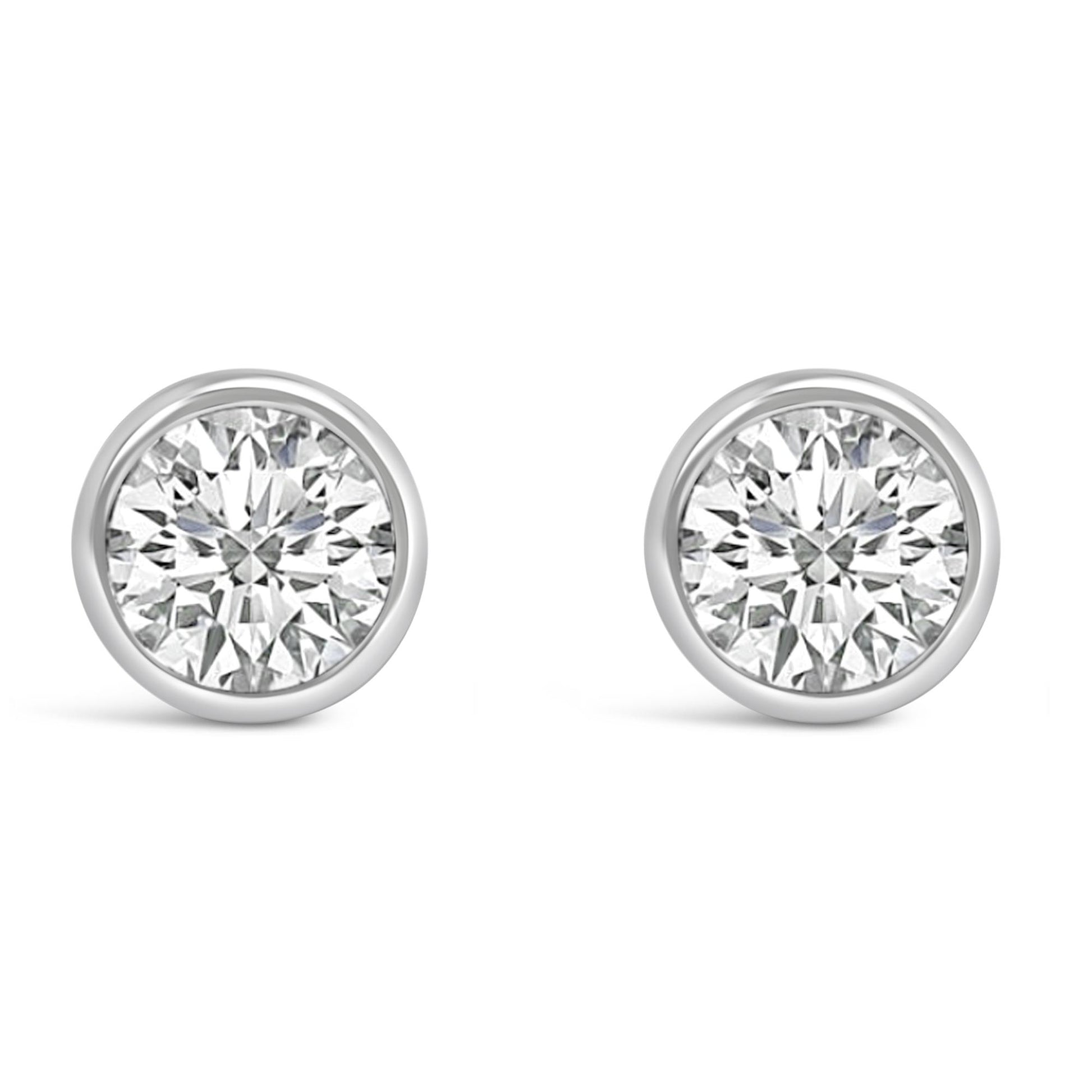 Front view of a pair of white metal bezel-set round white gemstone stud earrings.