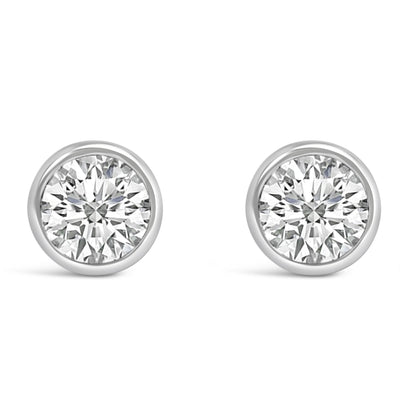 Front view of a pair of white metal bezel-set round white gemstone stud earrings.