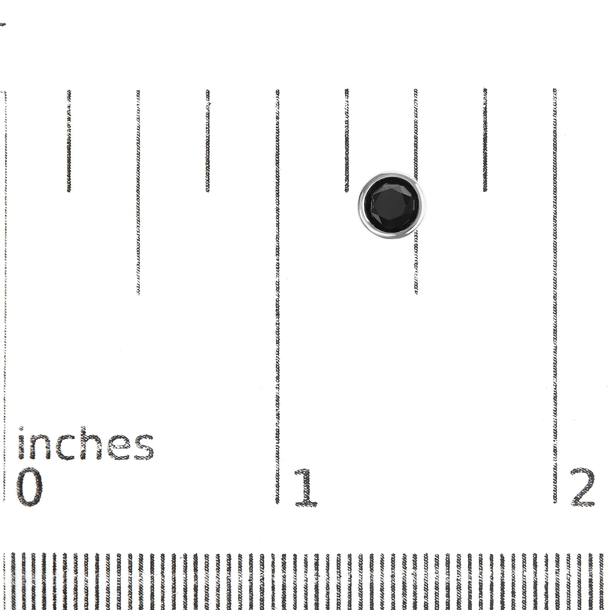 White metal earring with round black gemstone in bezel setting, shown on a ruler for size reference, top-down angle.