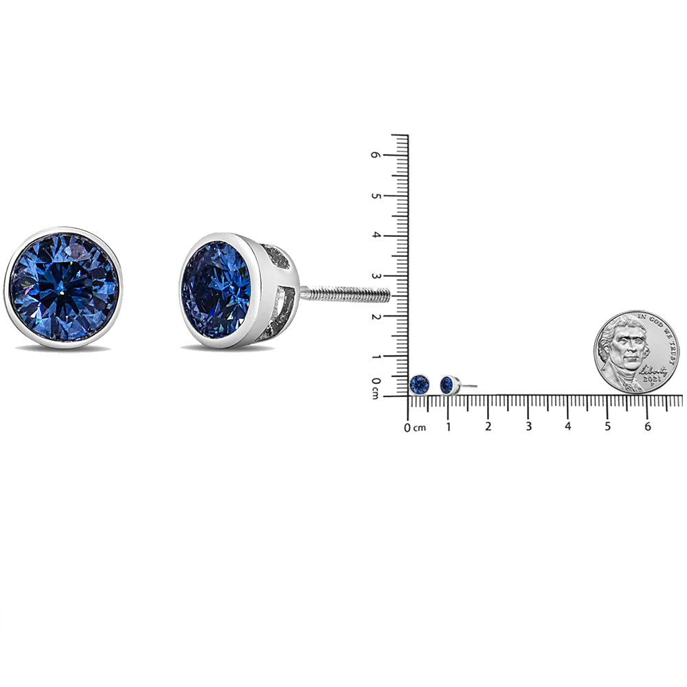 Pair of white metal stud earrings with round blue gemstones in bezel settings, shown from front and side angles, and displayed on a ruler for size reference.