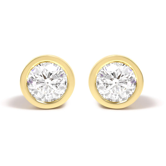 Front view of a pair of yellow metal stud earrings each featuring a round white gemstone in a bezel setting.