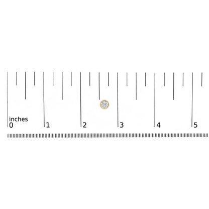 Close-up front view of a yellow metal round bezel-set white gemstone stud earring on a ruler for size reference.