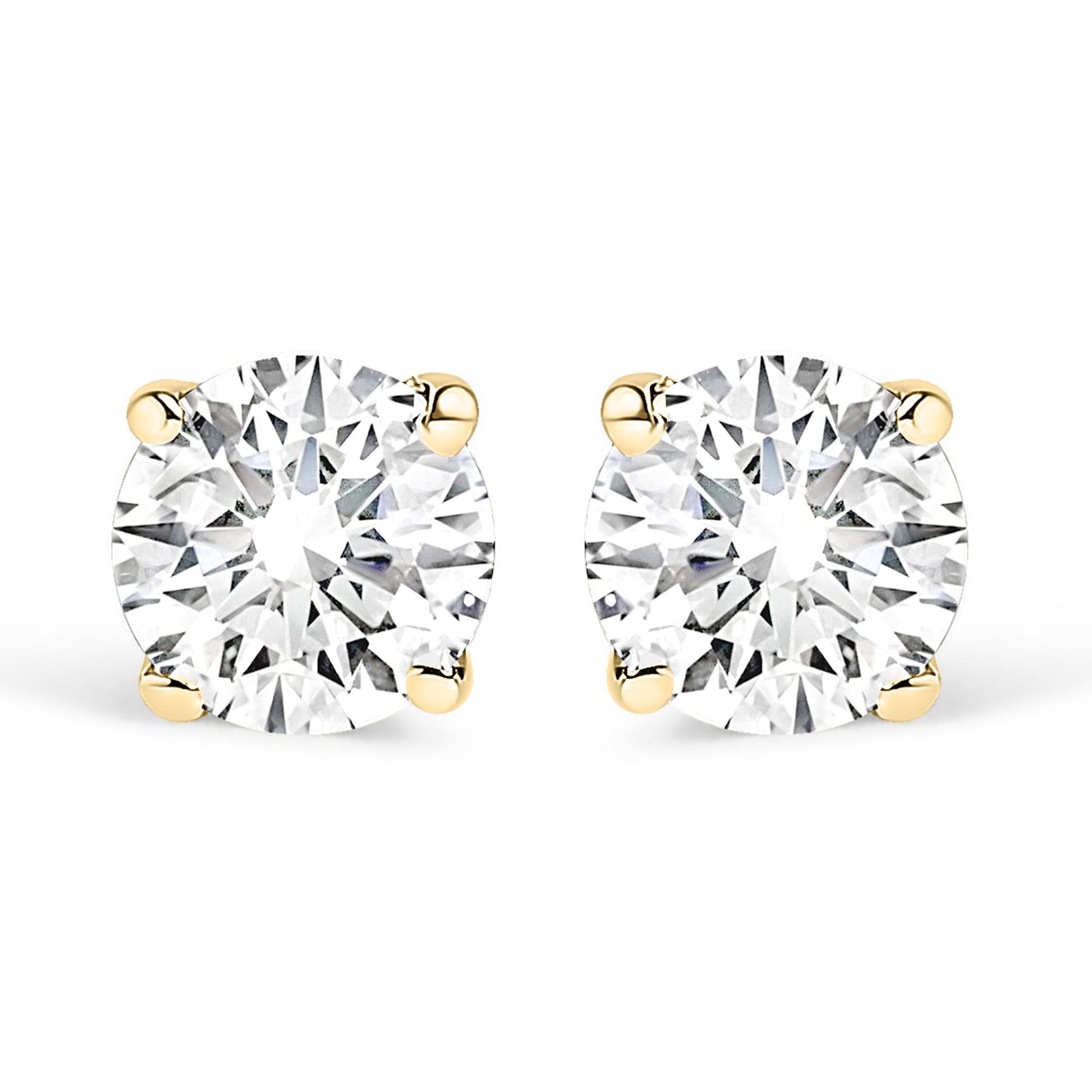 Front view of a pair of yellow metal stud earrings each set with a round white gemstone in a four-prong setting on a white background.