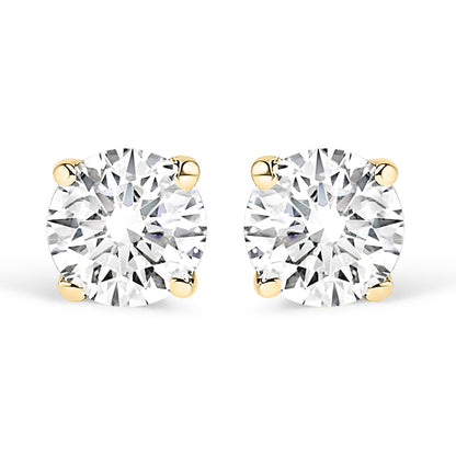 Front view of a pair of yellow metal stud earrings each set with a round white gemstone in a four-prong setting on a white background.