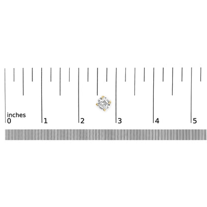 Yellow metal round stud earring with white gemstone in 4-prong setting shown on a scale from above.