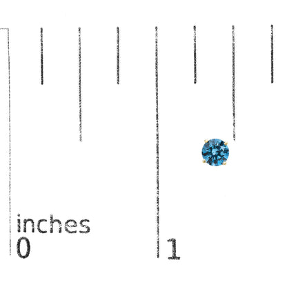 Close-up front view of a yellow metal stud earring with a round blue gemstone in a four-prong setting, placed on a ruler for size reference.
