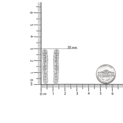 Pair of white metal hoop earrings with round white gemstones in prong settings, shown from front angle on a ruler for size reference.