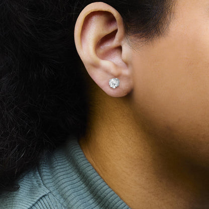 Close-up side view of a model wearing a white metal stud earring with multiple round white gemstones in a prong setting.