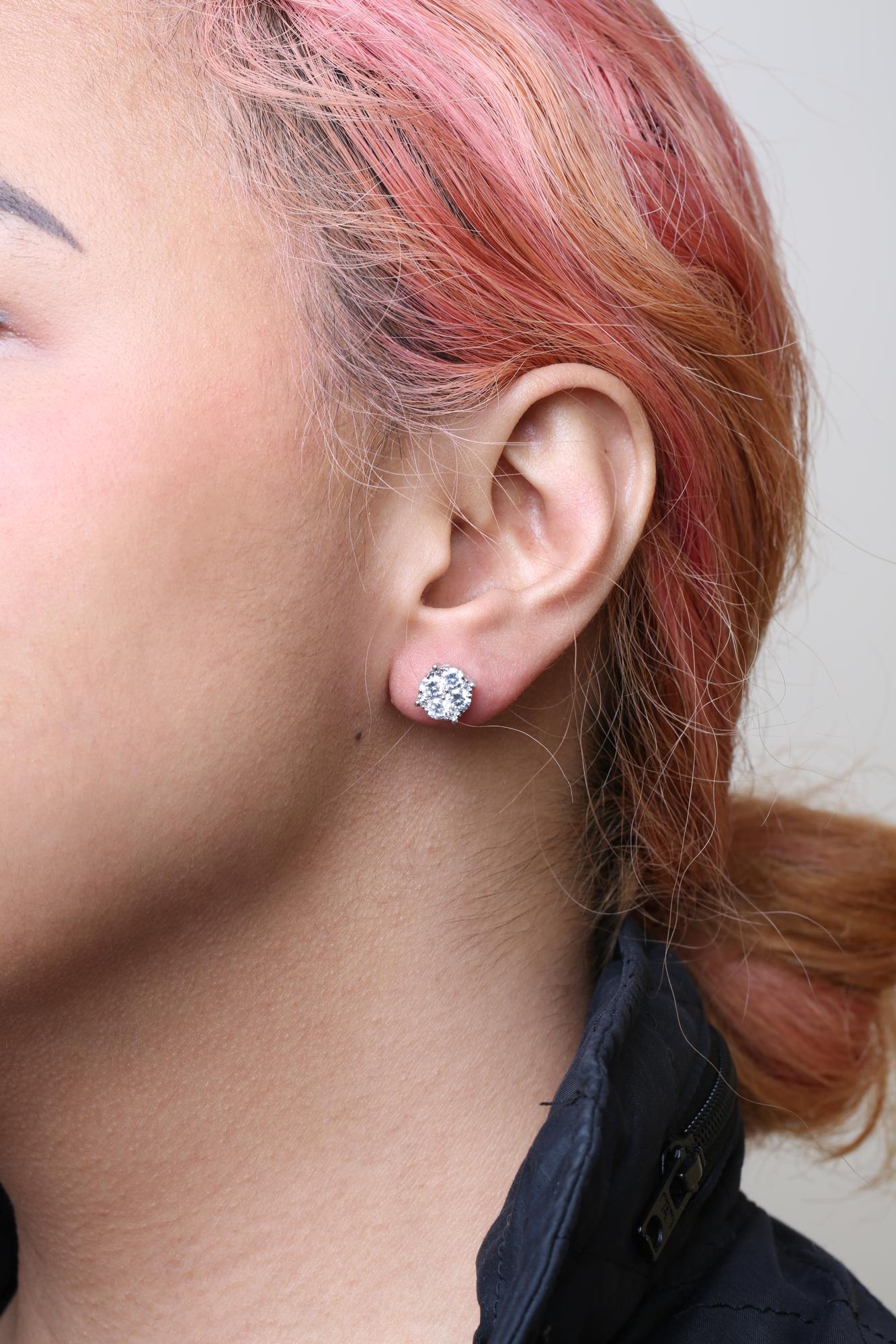 Close-up side view of a model wearing a white metal stud earring with multiple round white gemstones in prong settings.