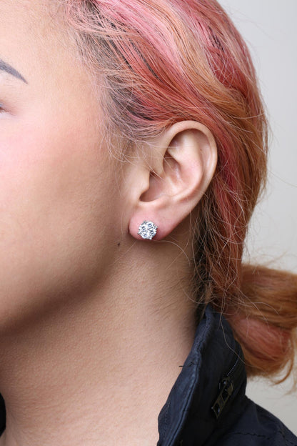 Close-up side view of a model wearing a white metal stud earring with multiple round white gemstones in prong settings.