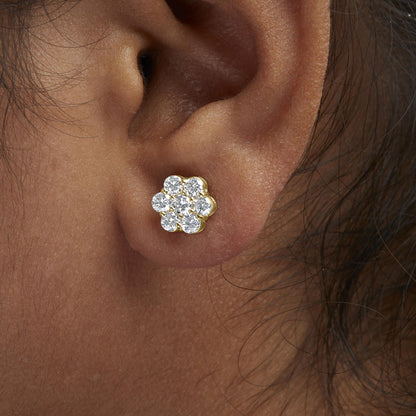Close-up side view of a yellow metal earring on a model's ear, featuring a cluster of round white gemstones in prong settings.