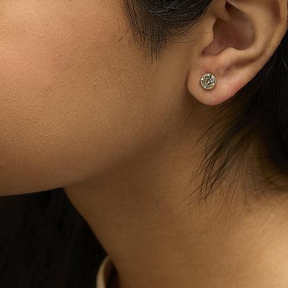 Close-up side view of a yellow stud earring with a round brownish gemstone in prong setting, worn on a model's ear.