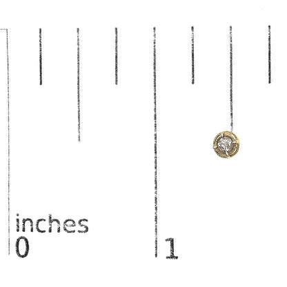 Close-up front angle of a yellow metal stud earring with a round brownish gemstone in a prong setting, placed on a ruler for size reference.