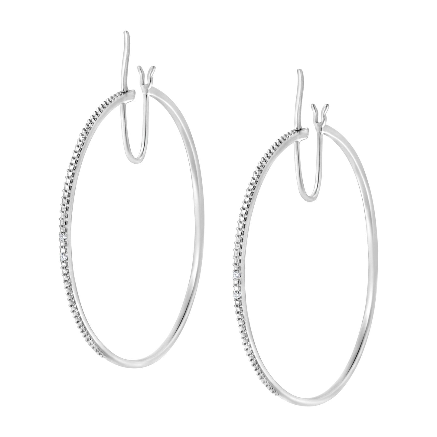 Front angled view of a pair of white metal hoop earrings with a section of round white gemstones in prong settings along the front curve.
