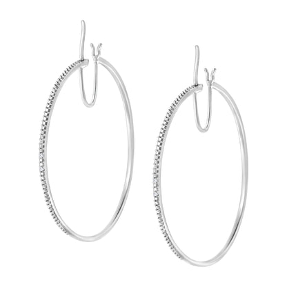 Front angled view of a pair of white metal hoop earrings with a section of round white gemstones in prong settings along the front curve.