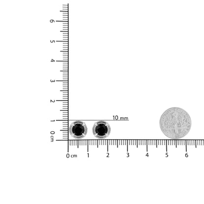 Pair of white metal stud earrings with round black gemstones in prong settings, shown on a ruler and scale for size reference, front angle.