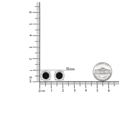 Pair of white metal stud earrings with black round gemstones in prong settings shown from the front, placed on a ruler for size reference with a coin nearby.