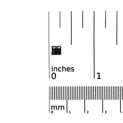 Close-up top view of a white metal earring with a black square-shaped gemstone in prong setting, placed on a ruler for size reference.