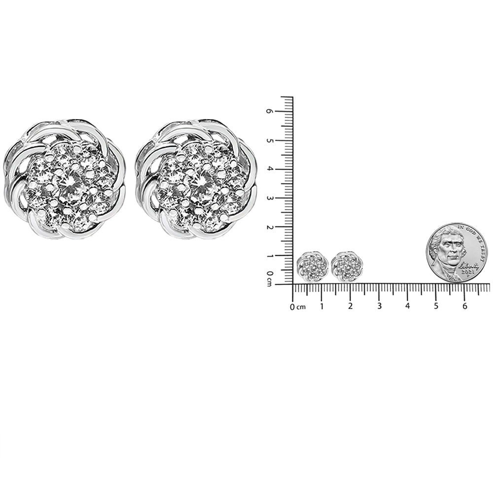 Pair of white metal earrings with round white gemstones in prong settings arranged in a flower pattern, shown from the front and side on a ruler for size reference.