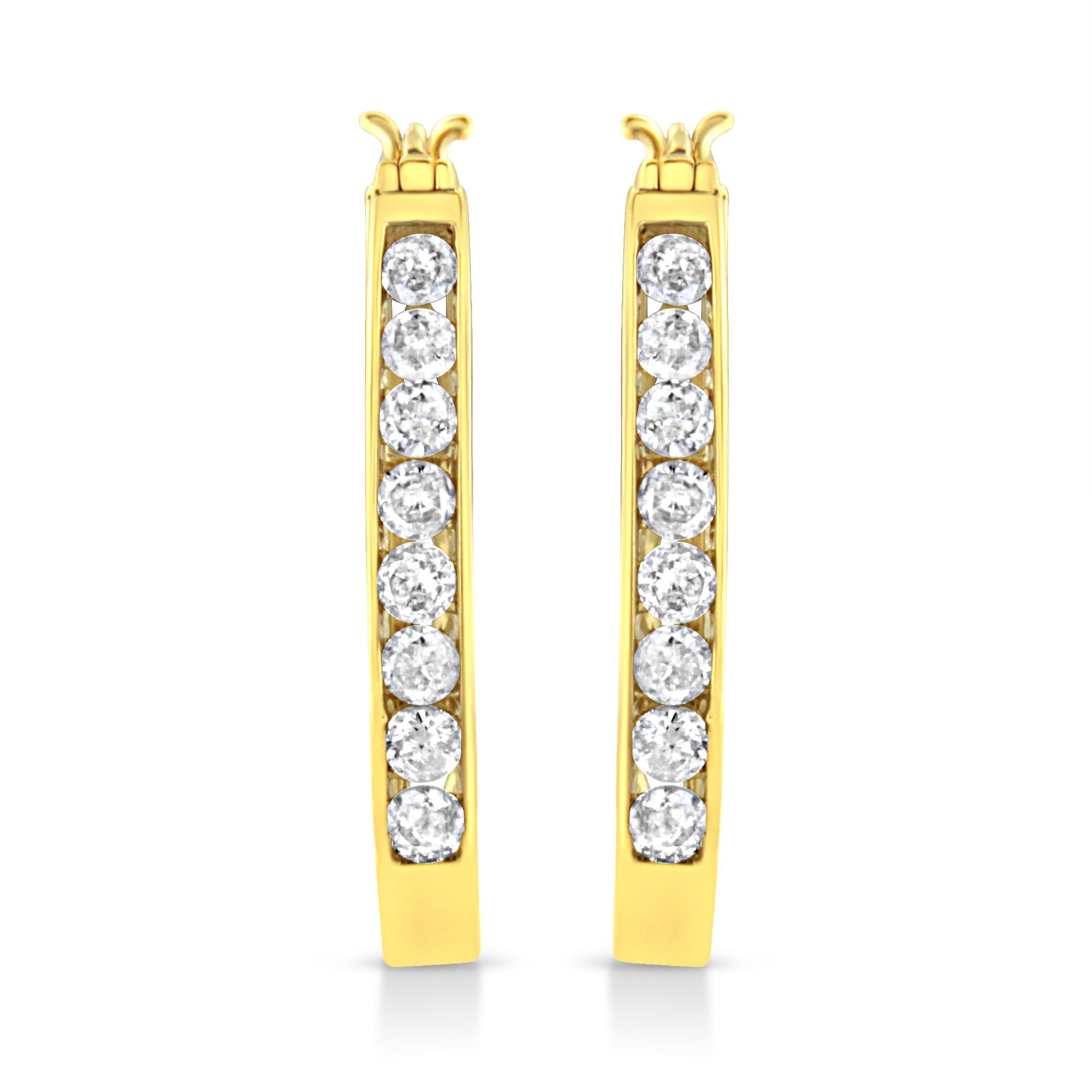 Front-facing view of a pair of yellow metal hoop earrings with a vertical row of round white gemstones set in a channel setting.