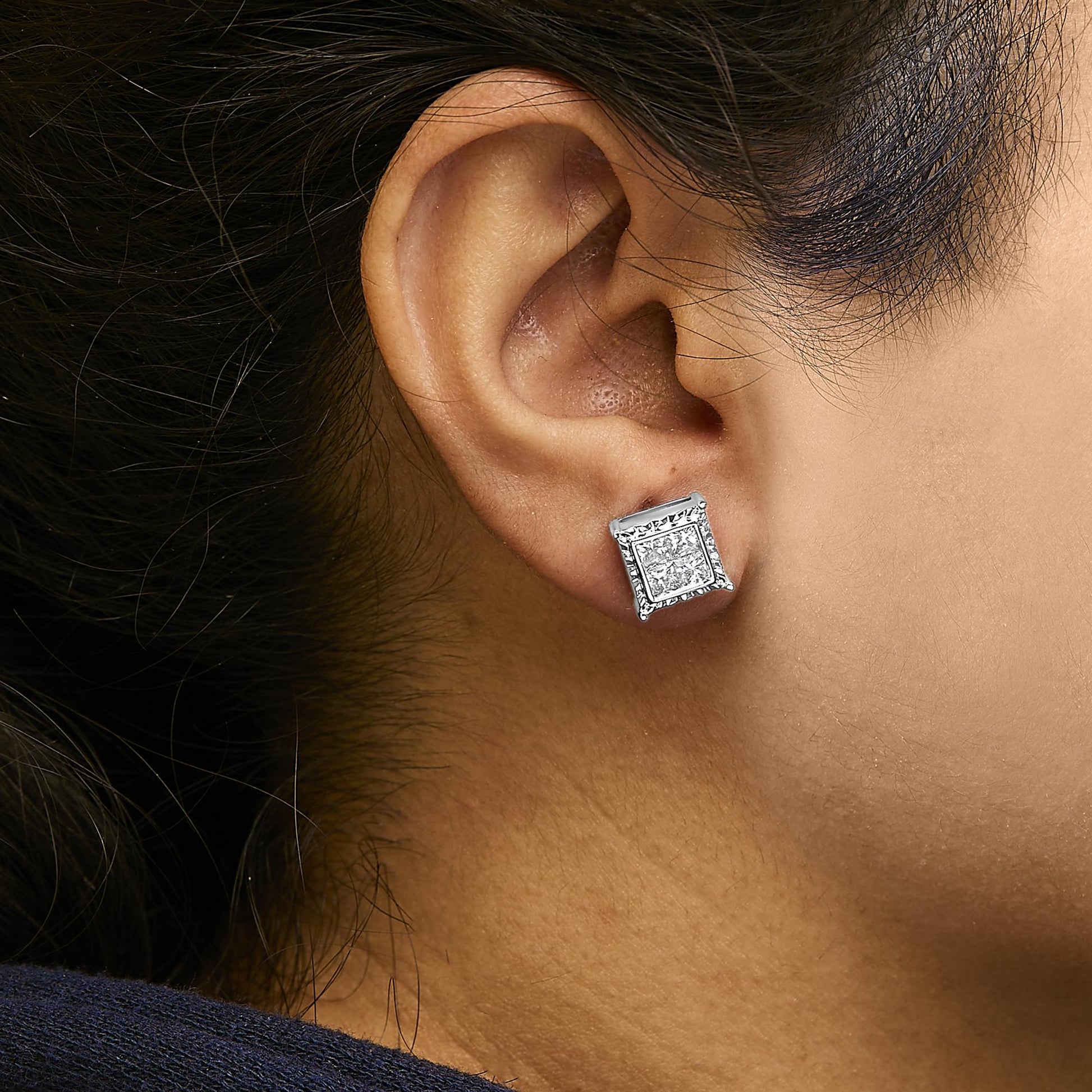 Close-up profile of a woman wearing white metal earrings with princess shape white gemstones in an invisible setting.