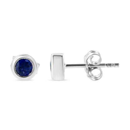 Pair of white metal stud earrings with round blue gemstones in bezel settings, shown from front and side angles.