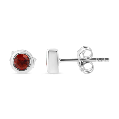 Pair of white metal stud earrings with round red gemstones in bezel settings, shown from front and side angles on a white background.