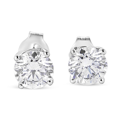 Front view of white metal stud earrings with round white gemstones in four-prong settings.