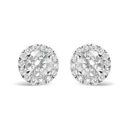Front view of a pair of white metal stud earrings each featuring a large round white gemstone surrounded by a halo of smaller round white gemstones in prong settings.