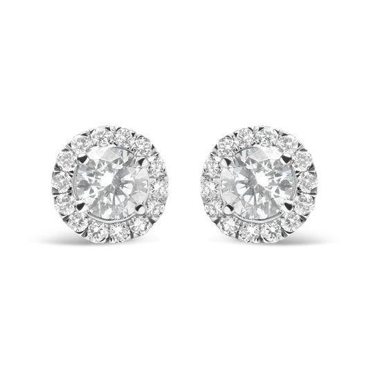 Front view of a pair of white metal stud earrings each featuring a large round white gemstone surrounded by a halo of smaller round white gemstones in prong settings.