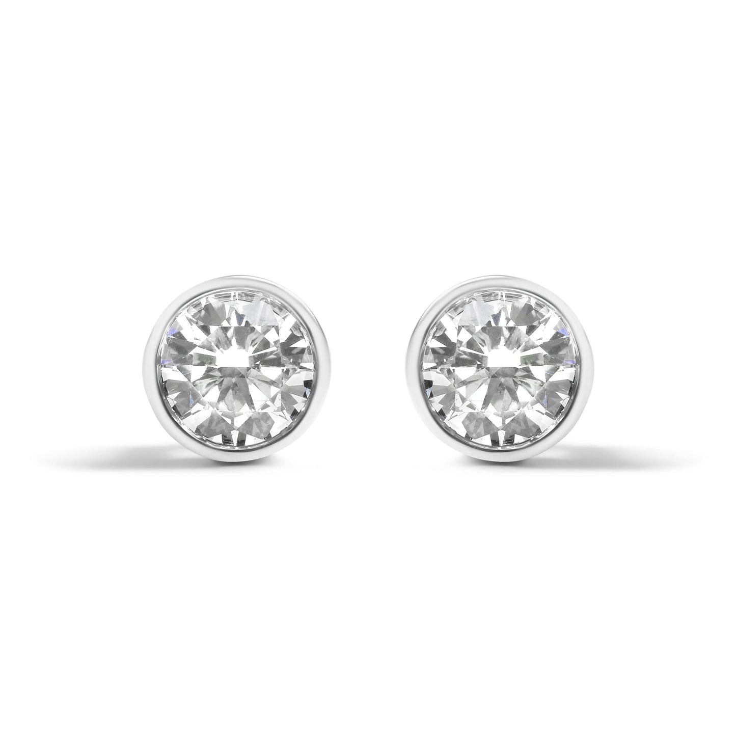 Front view of a pair of white metal round-shaped bezel set earrings with white gemstones.