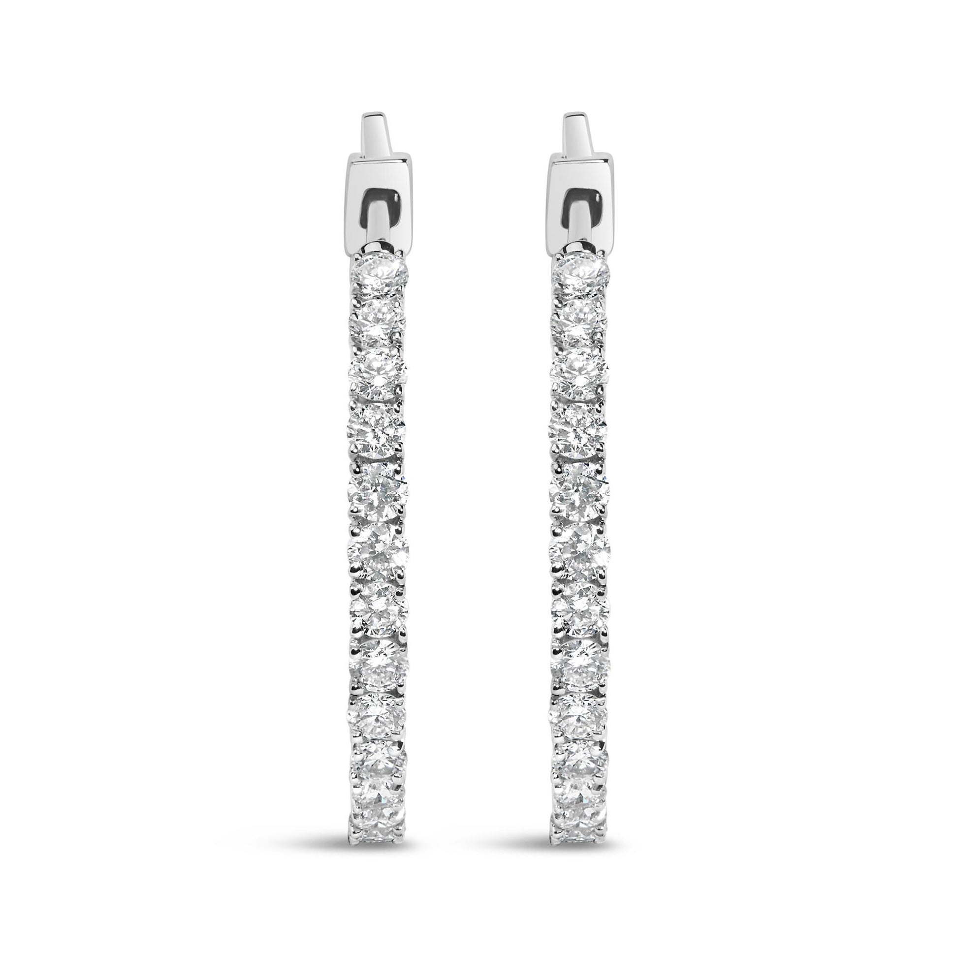 Front-facing view of white metal hoop earrings encrusted with round white gemstones in prong settings.
