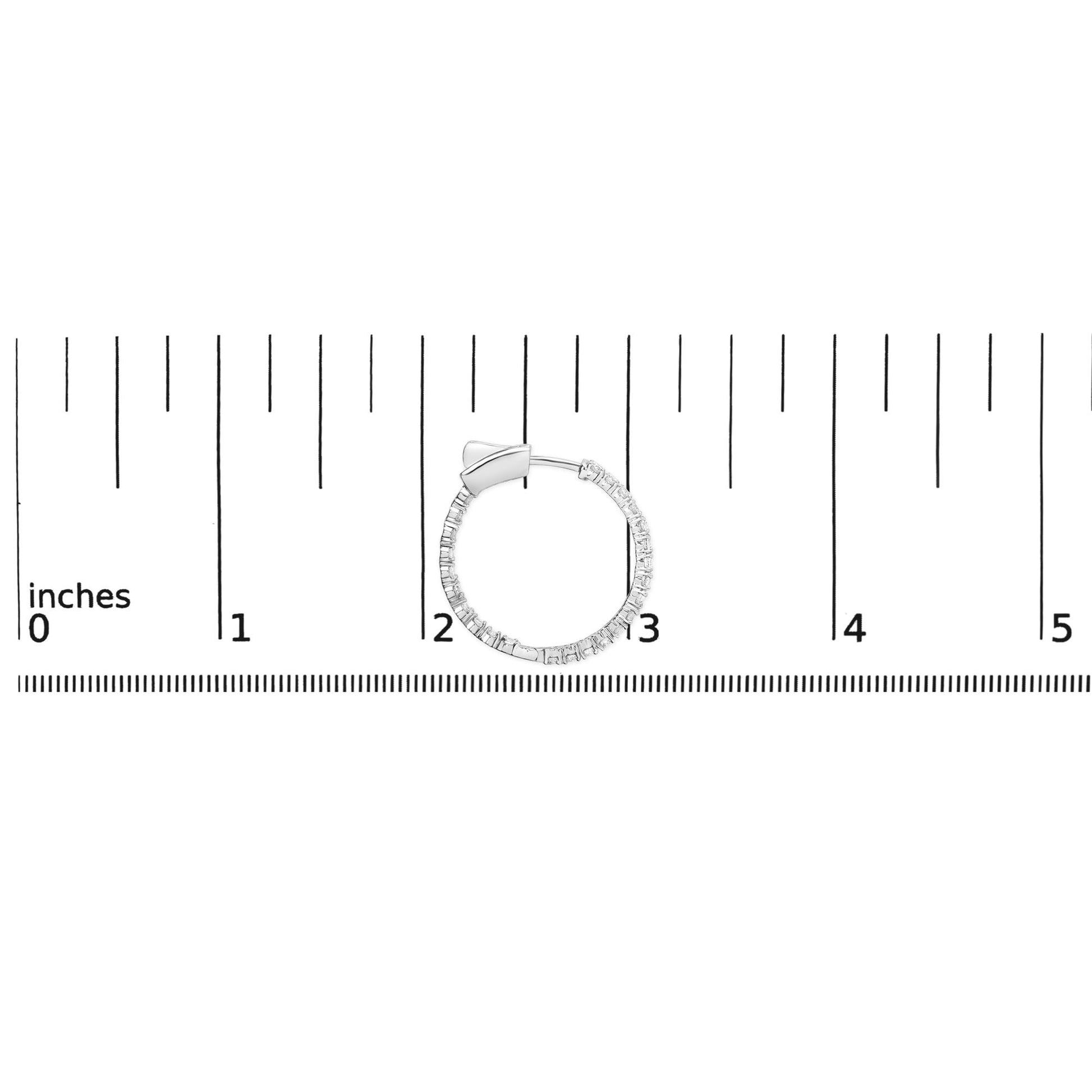 White metal hoop earring with round white gemstones in prong setting, shown from side angle on a ruler for size reference.