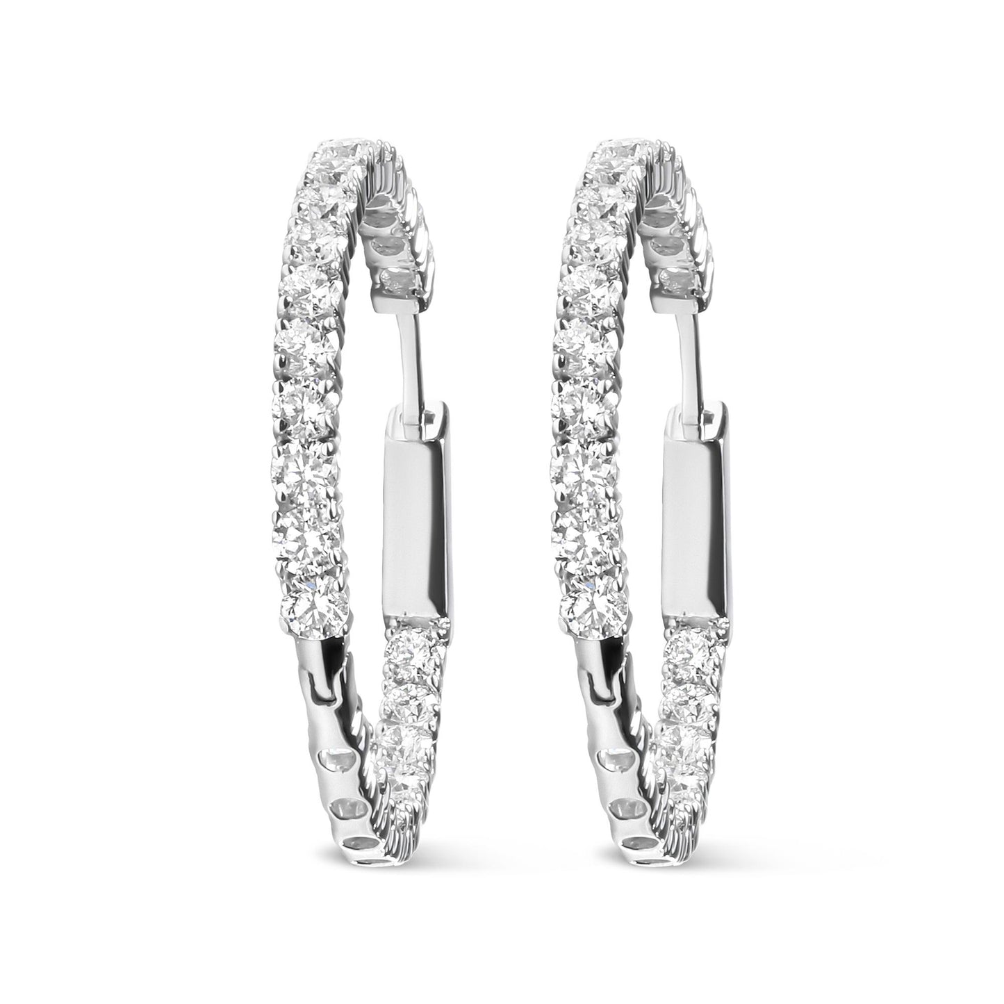 Pair of white metal hoop earrings with round white gemstones in prong settings, shown from a front angle.