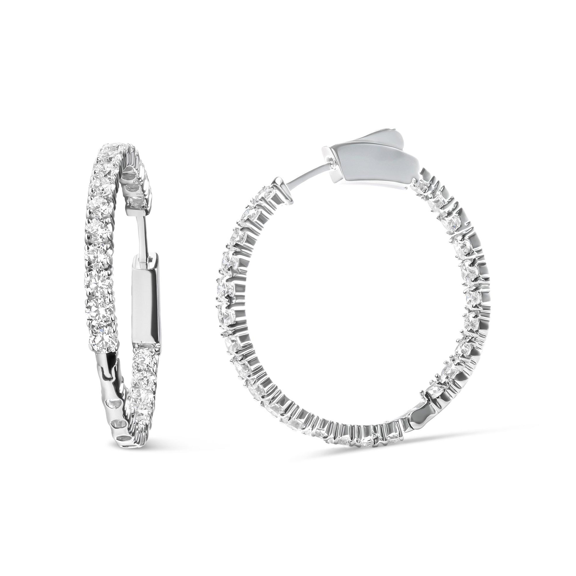 Pair of white metal hoop earrings with round white gemstones in prong settings, shown upright and flat with a side and front view on a white background.