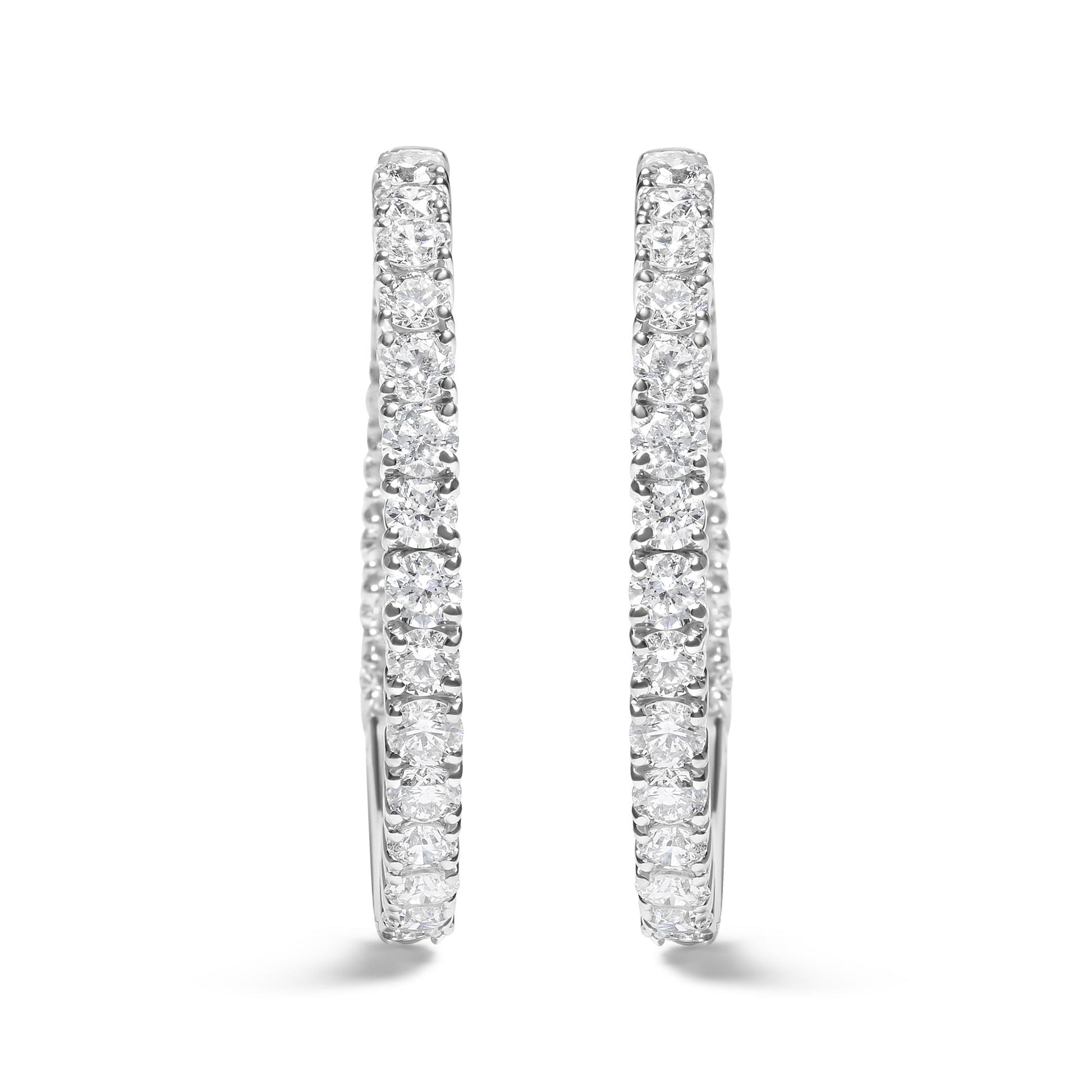Front-facing close-up of a pair of white metal hoop earrings set with round white gemstones in prong settings.