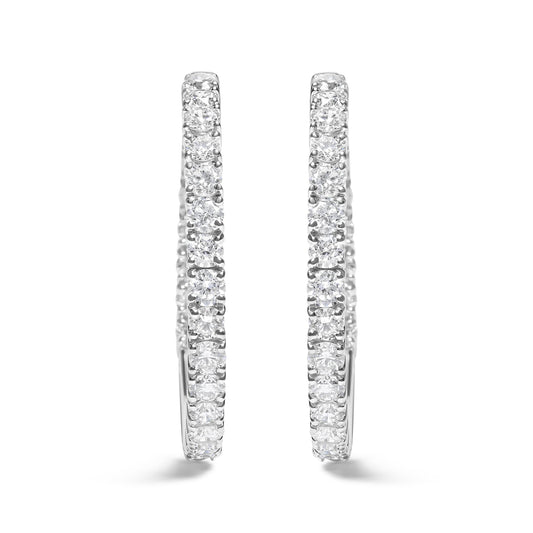 Front-facing close-up of a pair of white metal hoop earrings set with round white gemstones in prong settings.