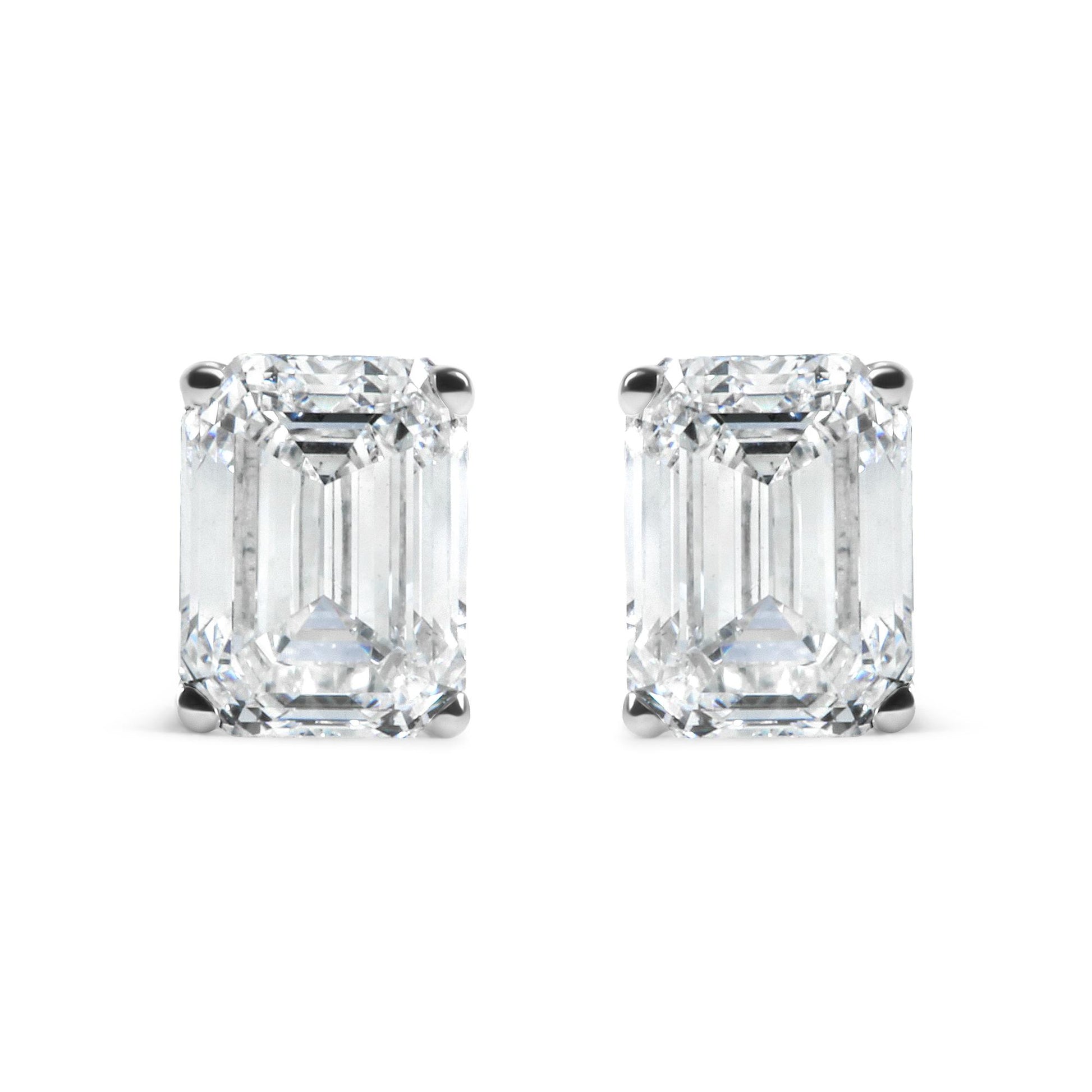 Pair of white metal earrings with emerald shaped white gemstones in 4-prong settings, front facing shot on white background.