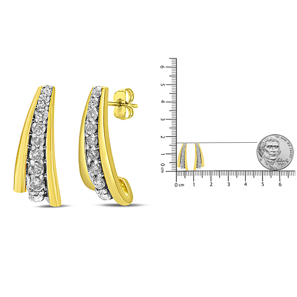 Yellow metal earrings with a curved design, featuring a row of round white gemstones set in prongs, shown at a slight angle next to a ruler and coin for size reference.
