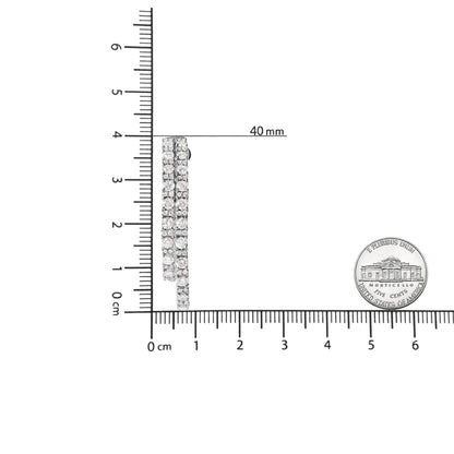Side view of white metal earrings with three rows of round white gemstones in prong settings, shown on a ruler and next to a coin for size reference.